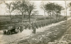 Soldaten im Auto, dahinter Soldaten-Hundertschaft mit Fahrrädern