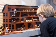kleiner Junge vor einem Gebäude aus Legosteinen