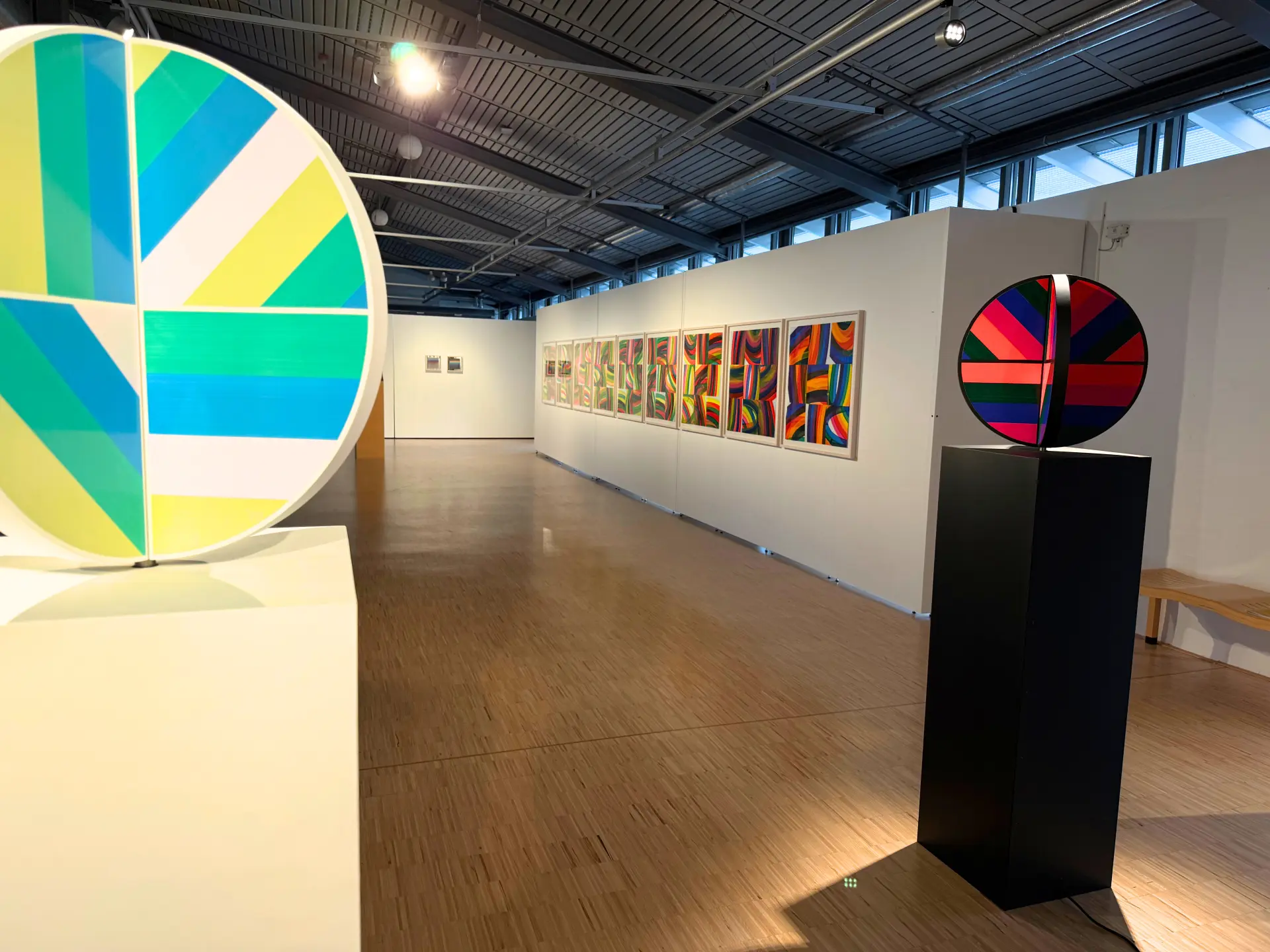 Das Bild zeigt eine bunte Kugel und bunte Bilder an einer Wand. 