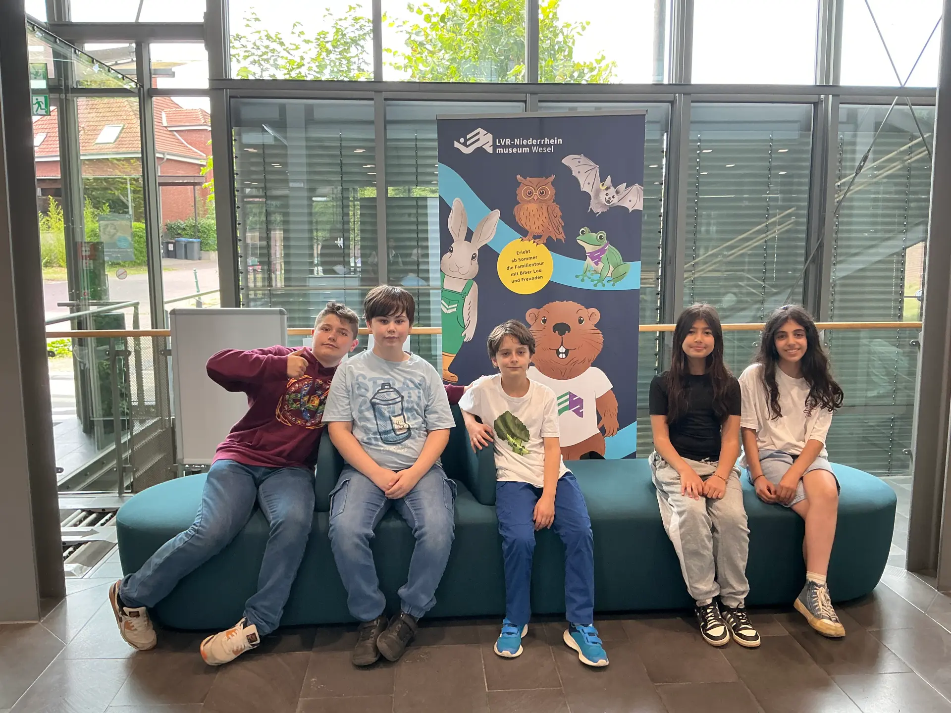 Eine Schulklasse sitzt im Foyer auf einem Sofa.