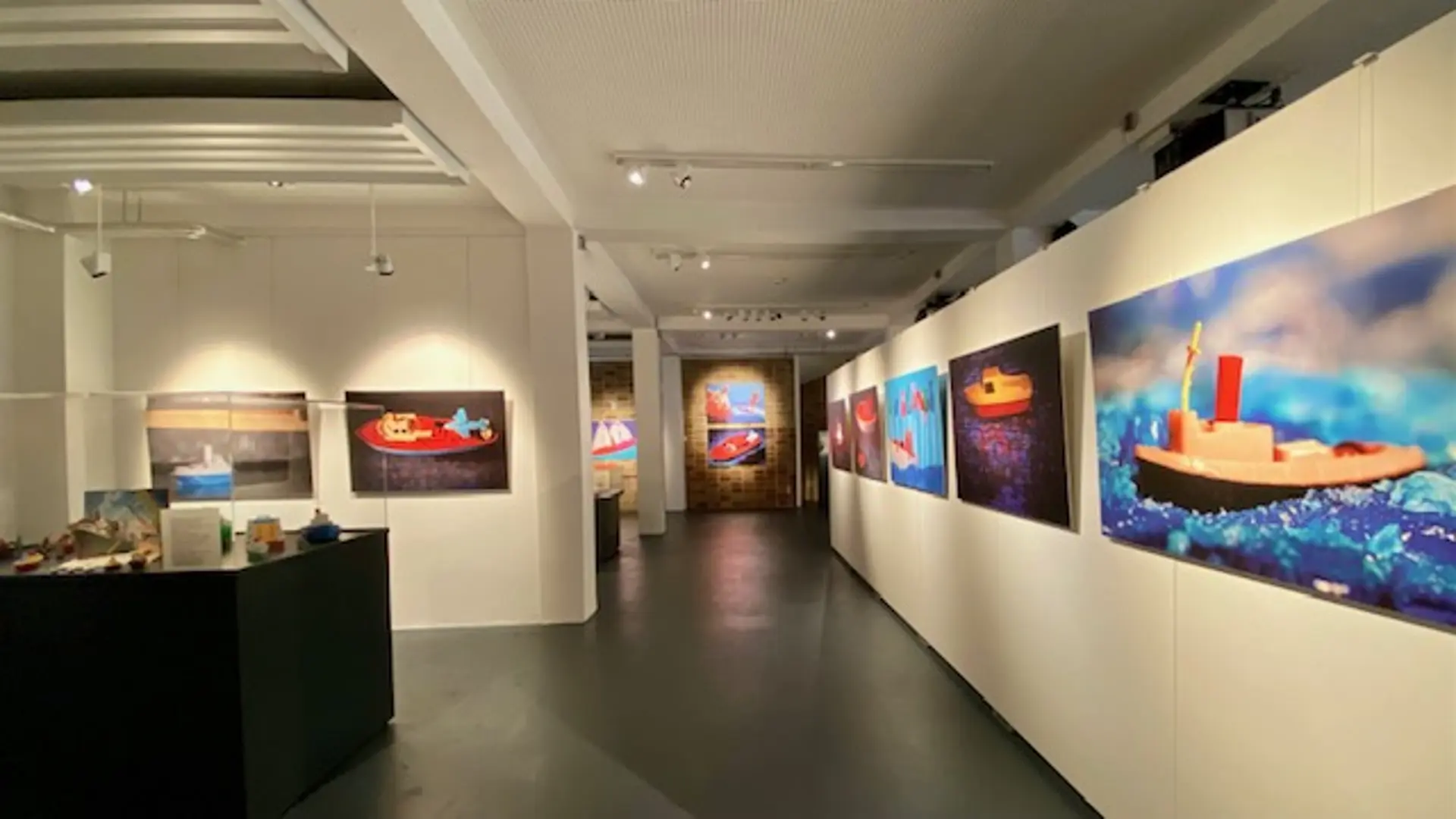 Die Ausstellung Leinen los zeigt verschiedene Fotos mit Spielzeugschiffen aus Plastik in einem Ausstellungsraum 